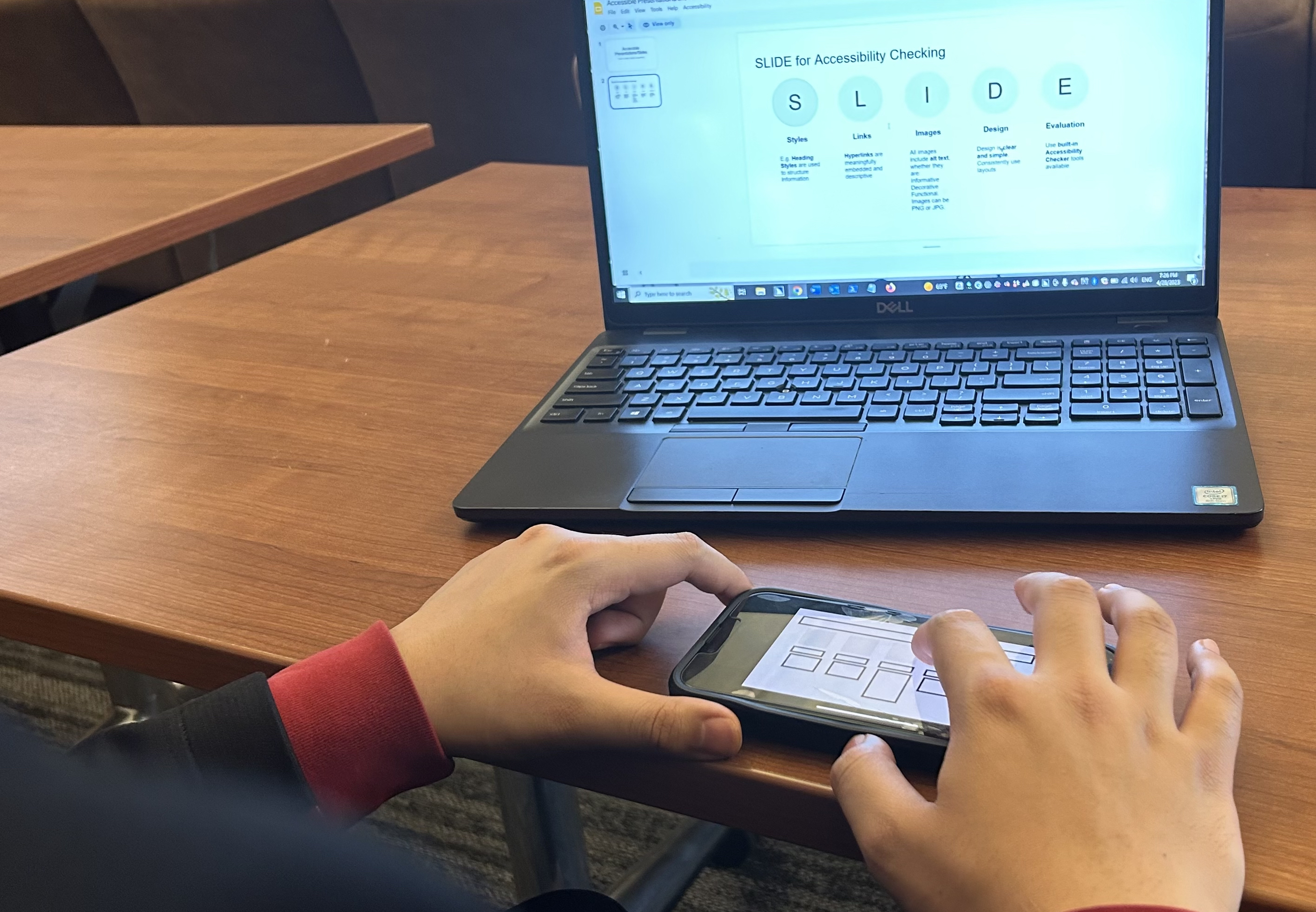 A blind user utilizing A11yBoard with a split setup: a laptop for keyboard commands and a smartphone for tactile spatial exploration.
